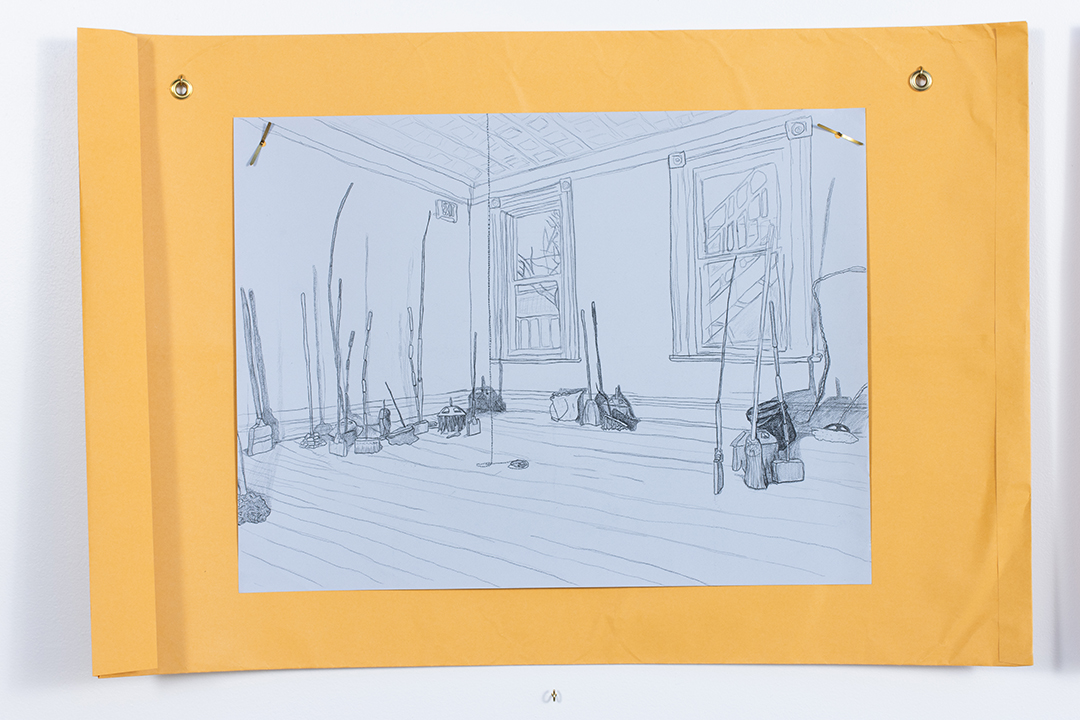 A large drawing on blue paper depicting a room with various broom-like objects in it, hung atop a large manila envelope.