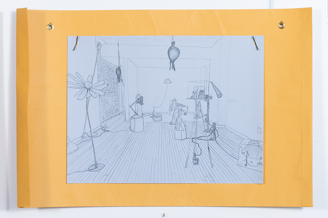 A large drawing on blue paper depicting a room with various lamp-like objects in it, hung atop a large manila envelope.